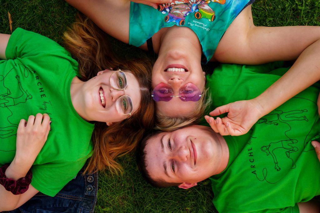 Pracownicy Fundacji: Ola, Marta, i Kamil leżą na trawie, uśmiechają się