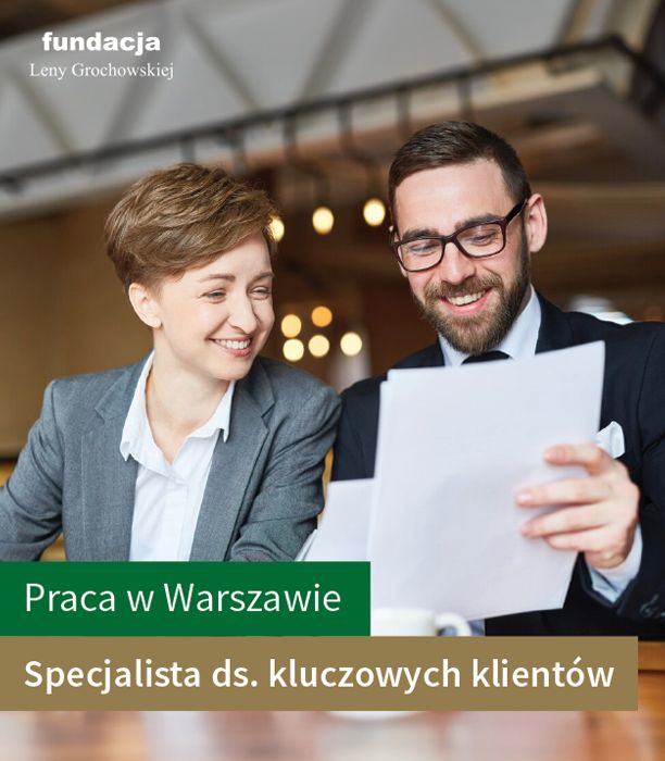Zdjęcie dwóch osób nad dokumentami w biurze. Uśmiechają się. Napis: Praca w Warszawie. Specjalista ds. kluczowych klientów