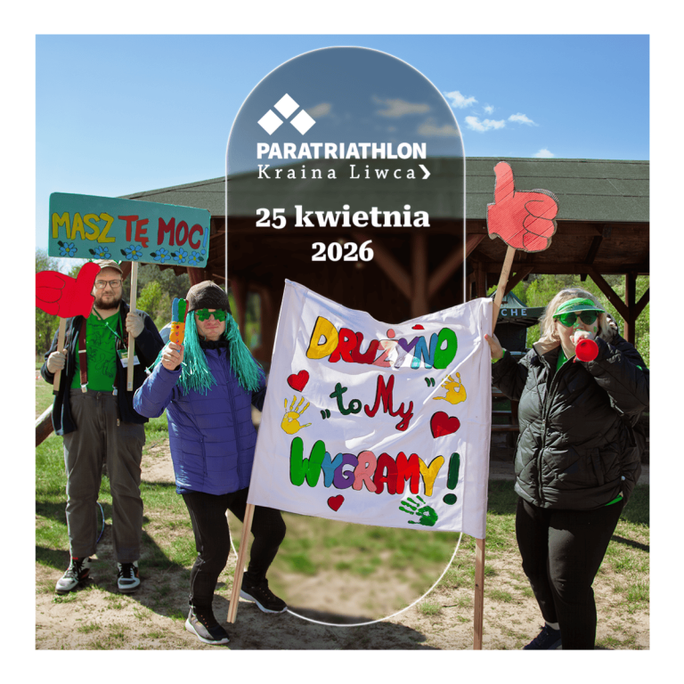Grupa kibicujących osób na świeżym powietrzu trzyma kolorowe transparenty. W tle informacja o wydarzeniu Paratriathlon Kraina Liwca -25 kwietnia 2026.